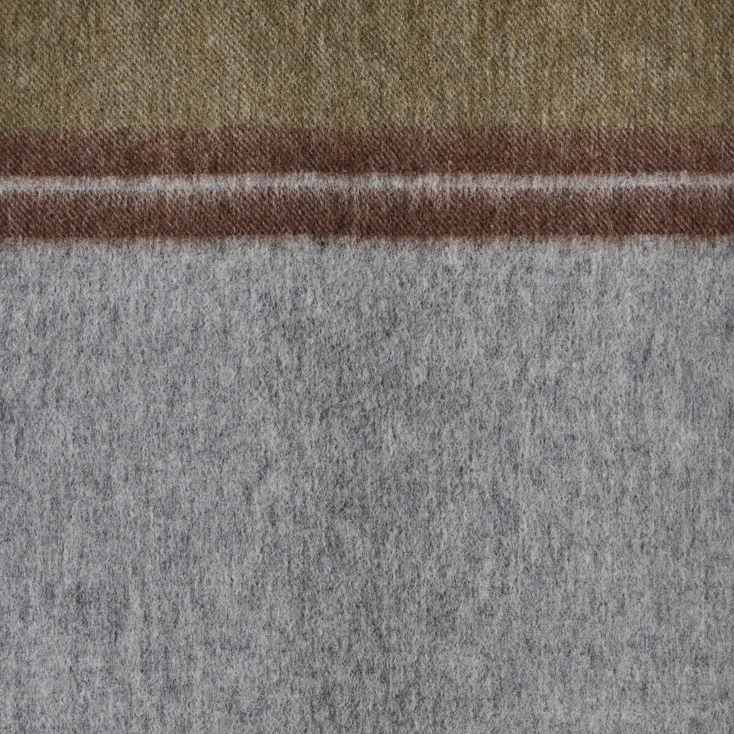 Close-up of a wool fabric with a brown stripe on a gray background