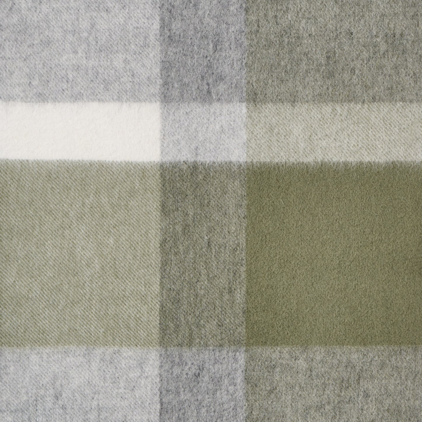 Close-up of a plaid wool fabric with green, grey, and white colours.