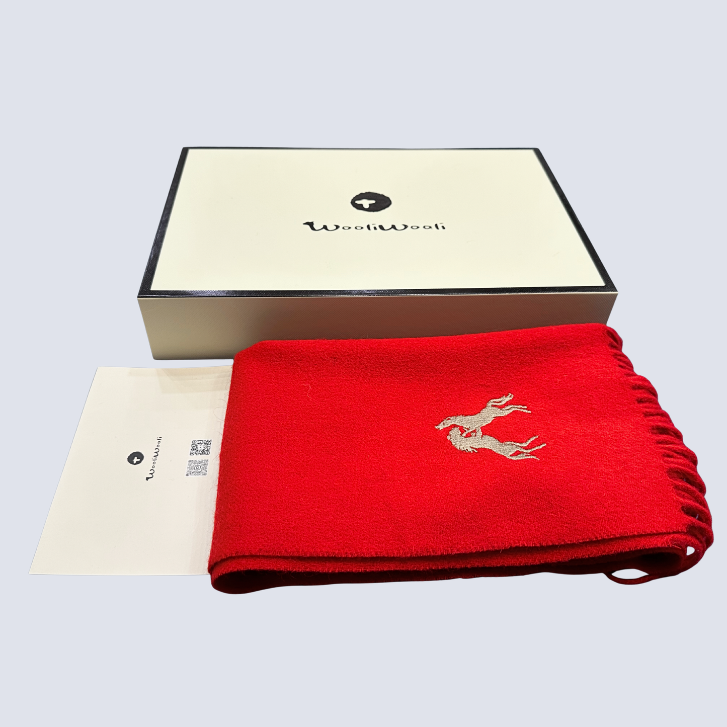 Red scarf with gold embroidery and a matching card on a gray background, featuring the WooliWooli brand.