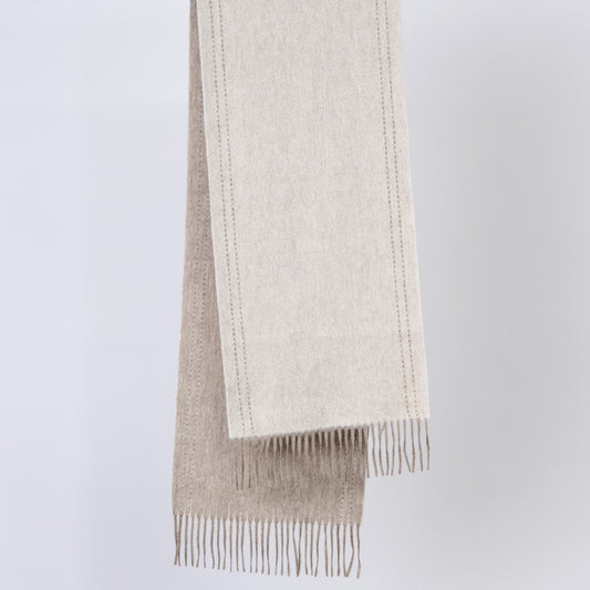 A beige scarves with fringes on a light gray background