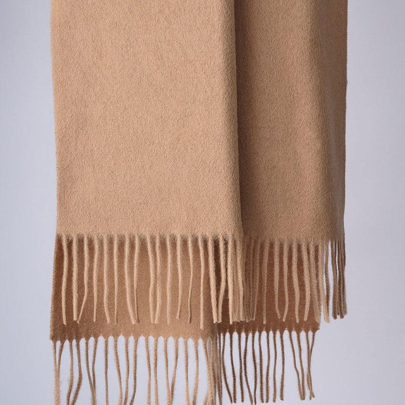 Beige shawl with fringes on a light gray background