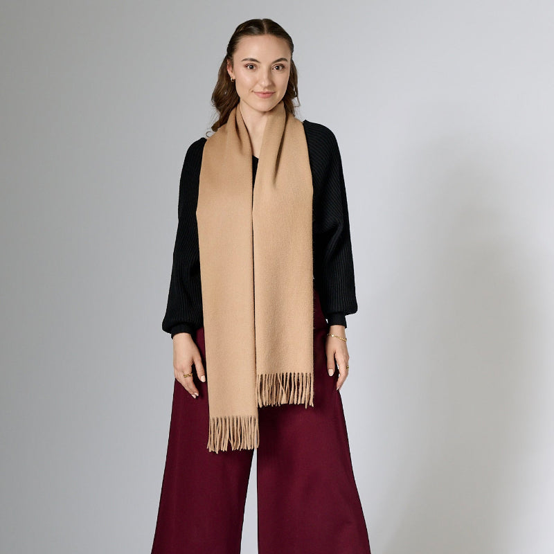 Woman wearing a beige scarf with a plain background