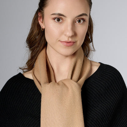 A woman wearing a light beige scarf with a neutral facial expression, looking straight ahead.