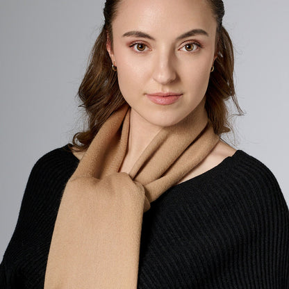 Woman wearing a beige scarf against a gray background