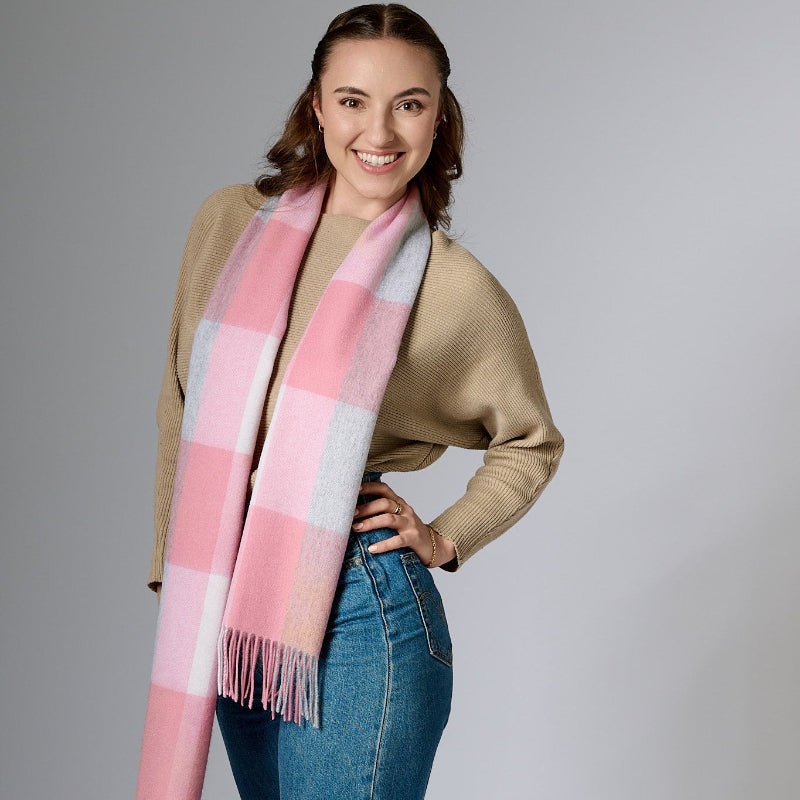 Woman wearing a pink and gray checkered scarf on a gray background