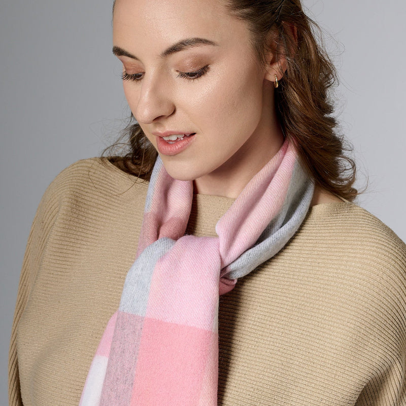 A woman wearing a pink and gray checkered scarf with a neutral background.