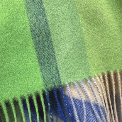 Close-up of a plaid fabric with green, blue, and beige colors.