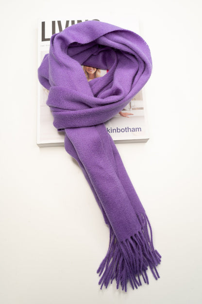 Purple wool scarf with tassels on a magazine