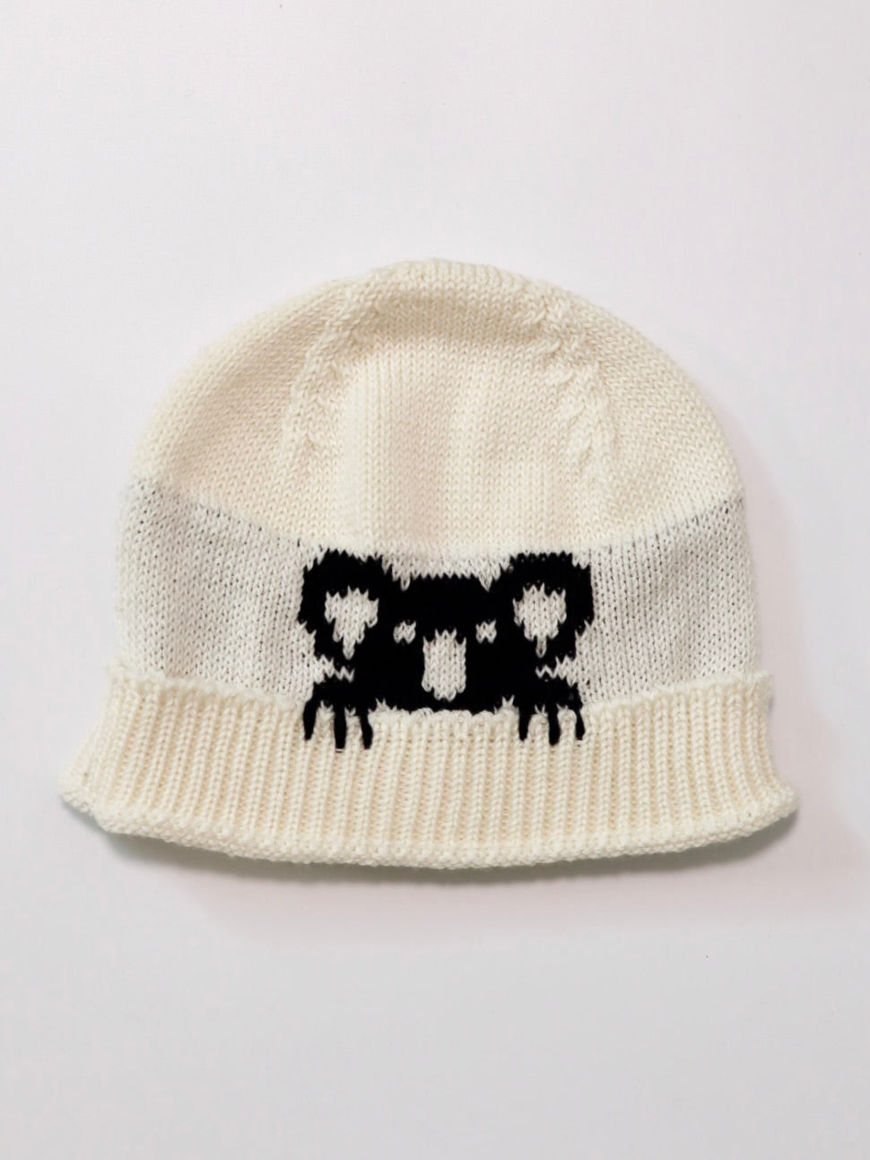 White knit beanie with black pattern on a light gray background