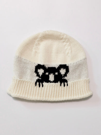 White knit beanie with black pattern on a light gray background