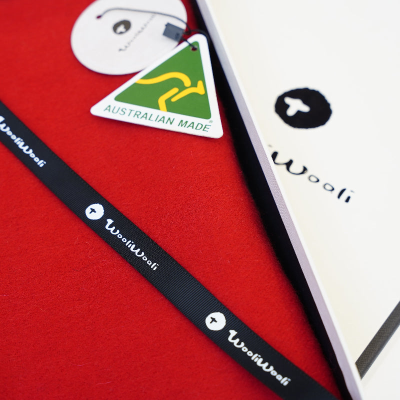Close-up of a red product with a black strap and 'Wooli' branding, featuring an Australian Made label.
