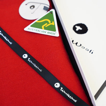 Close-up of a red product with a black strap and 'Wooli' branding, featuring an Australian Made label.