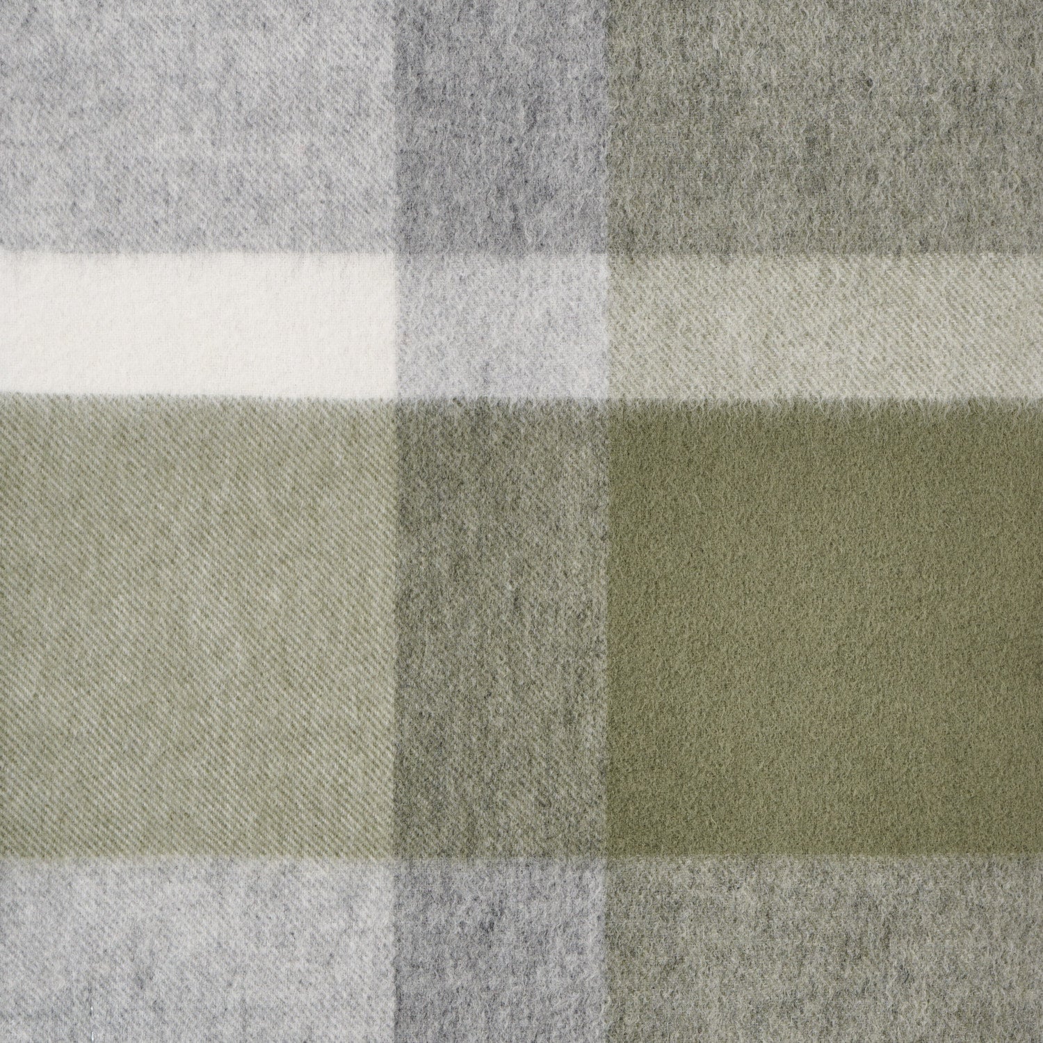Close-up of a plaid wool fabric with green, grey, and white colours.