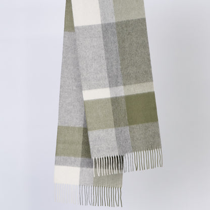 Plaid wool scarf with green, gray, and white colors on a light gray background