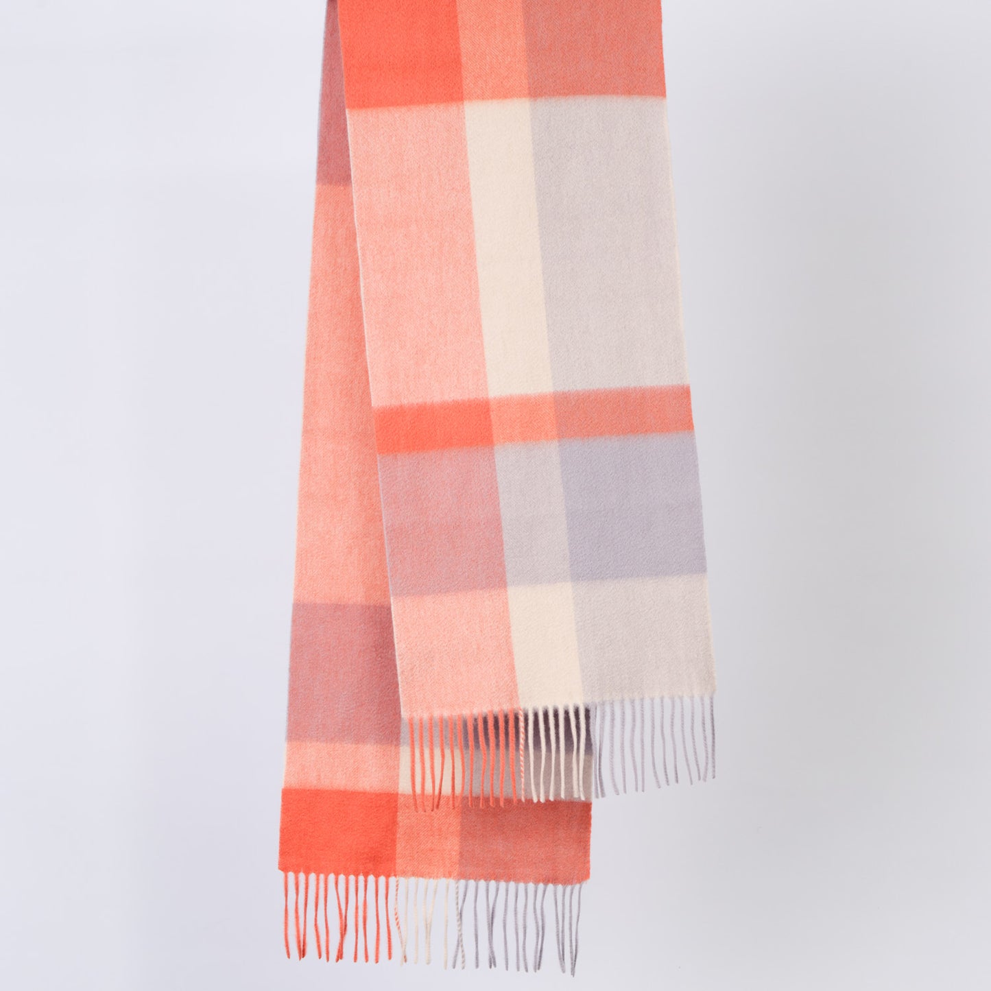 Plaid wool scarf with orange, pink, and gray colors on a light gray background
