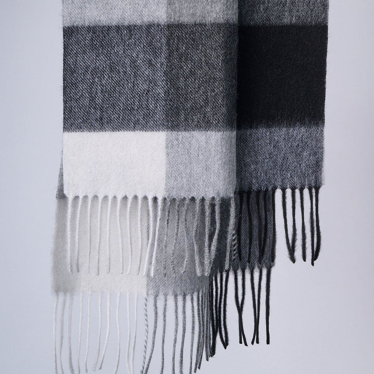 Plaid scarf with fringe details on a light gray background