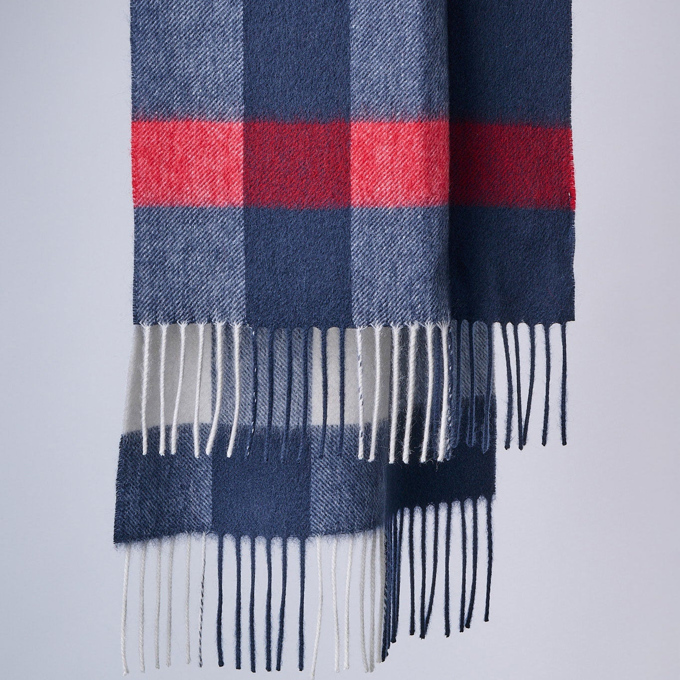 Plaid scarf with blue, red, and white colors on a light gray background
