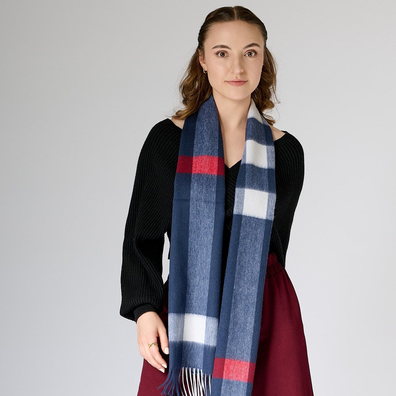 Woman wearing a blue, red, and white checkered scarf against a plain background