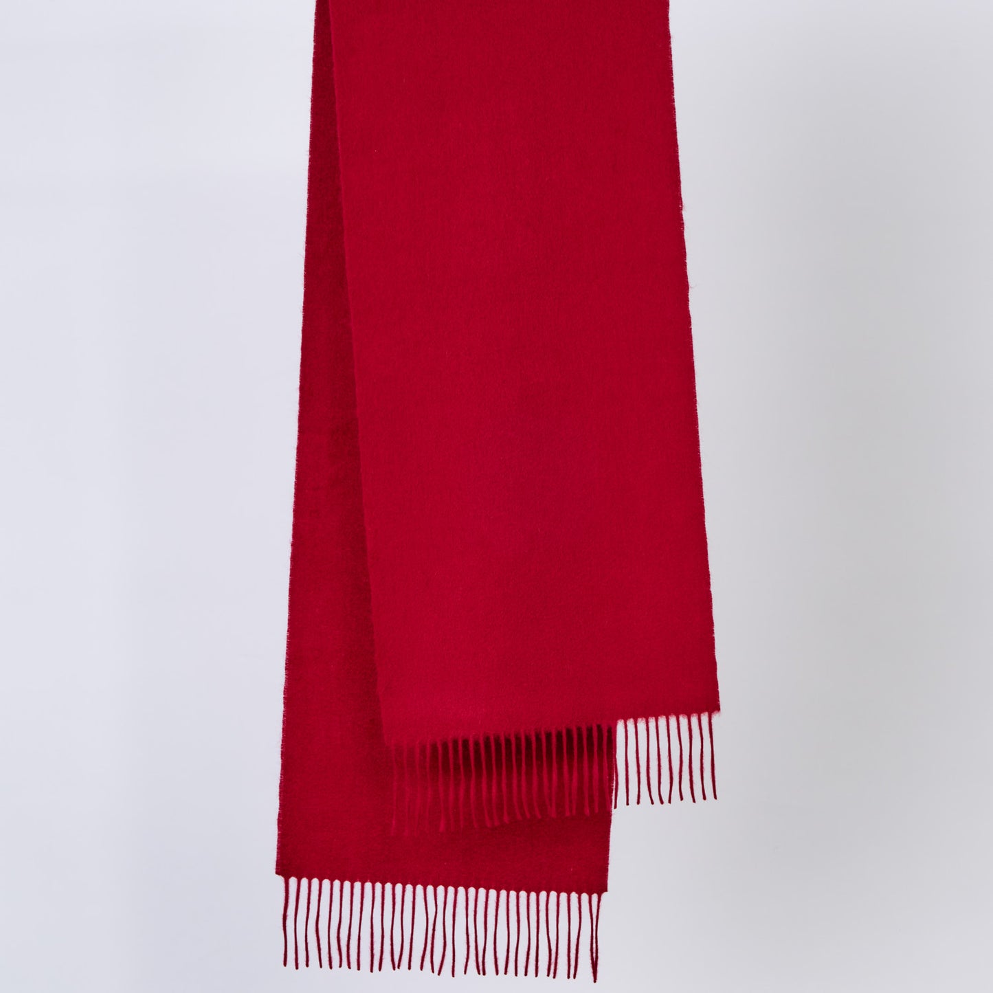 Burgundy red wool scarf with fringes on a light gray background