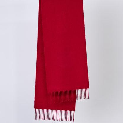 Burgundy red wool scarf with fringes on a light gray background