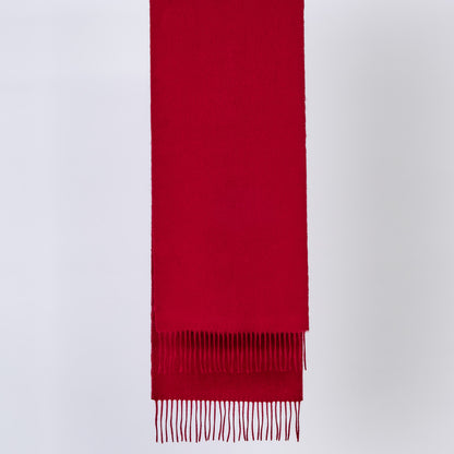 Burgundy red wool scarf with fringes on a light gray background