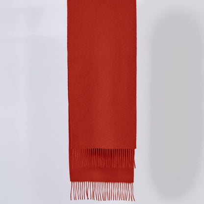Pumpkin red scarf with fringes on a light gray background