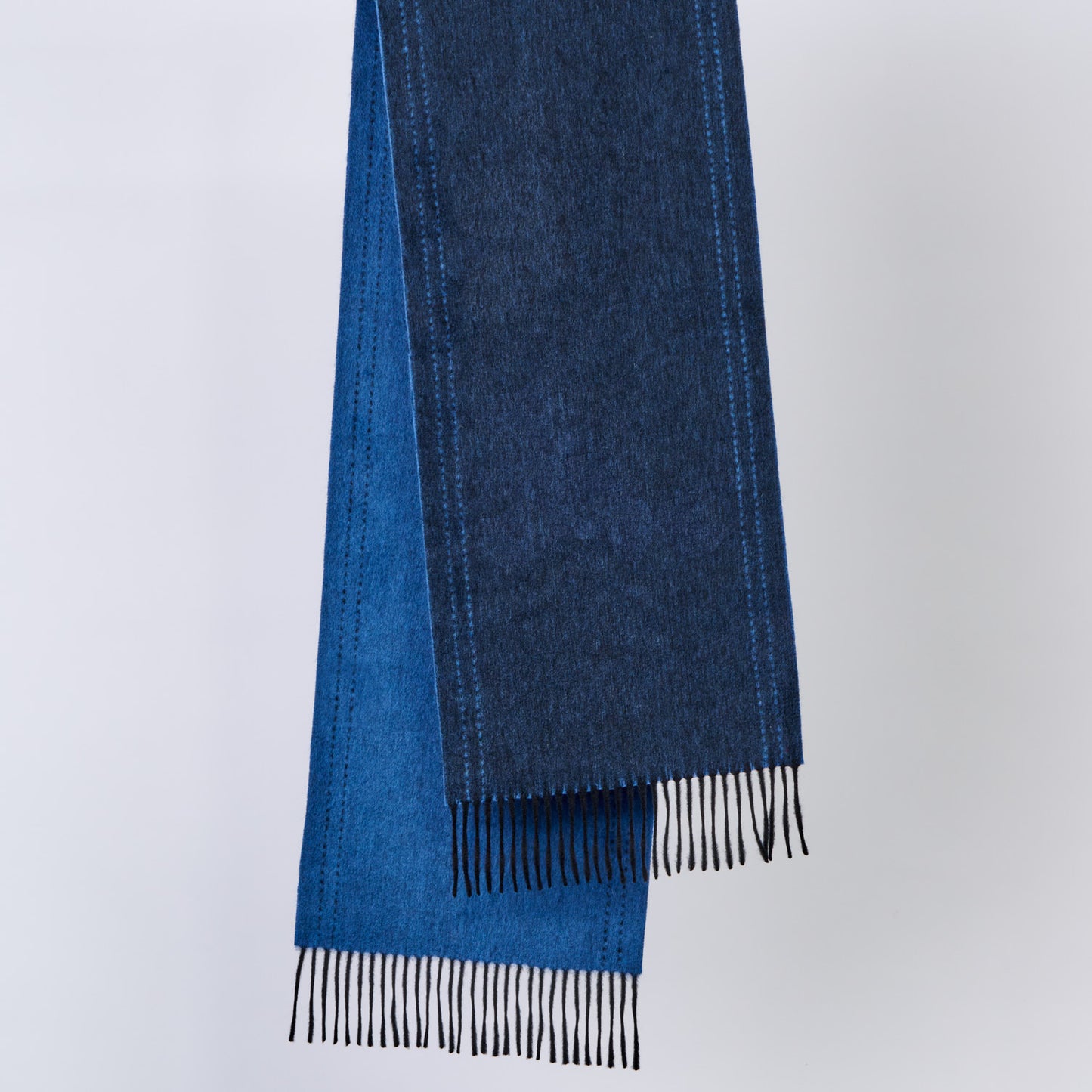 Blue wool scarf with black fringe on a light gray background