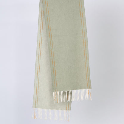 Green wool scarf with white fringe on a light gray background