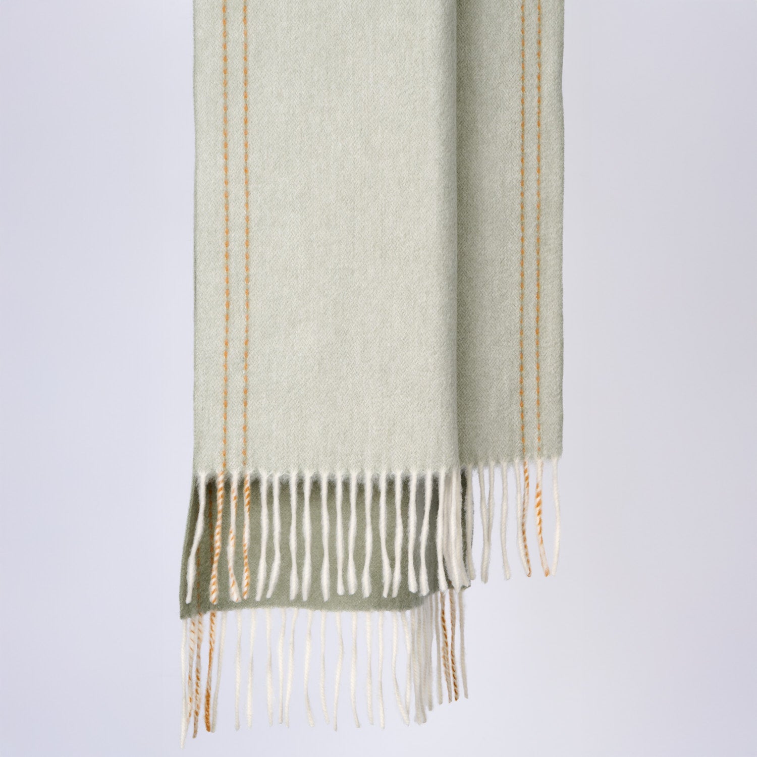 Green scarf with fringe on a light gray background