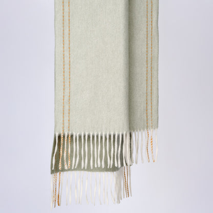 Green scarf with fringe on a light gray background