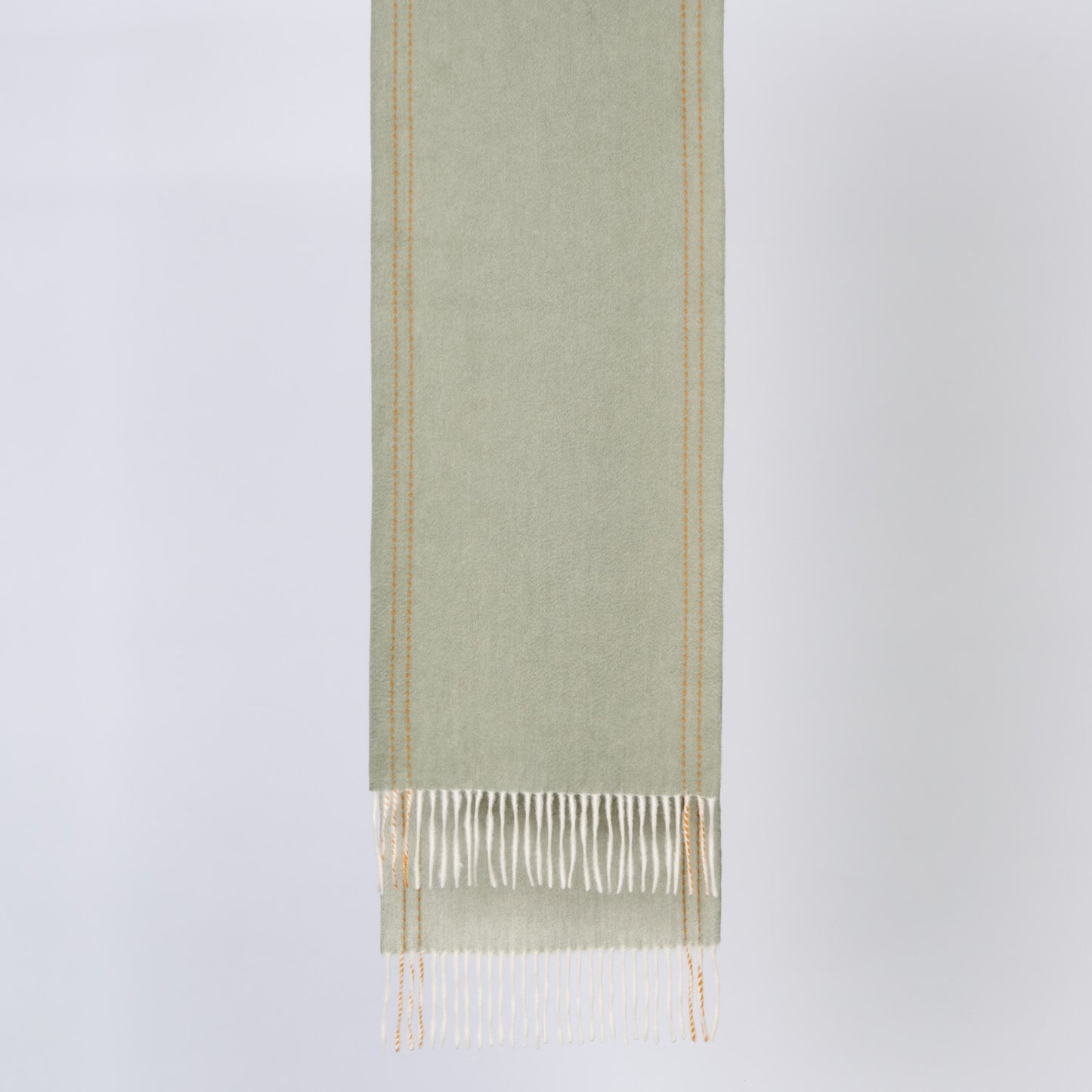 Green wool fabric with white fringe on a light gray background