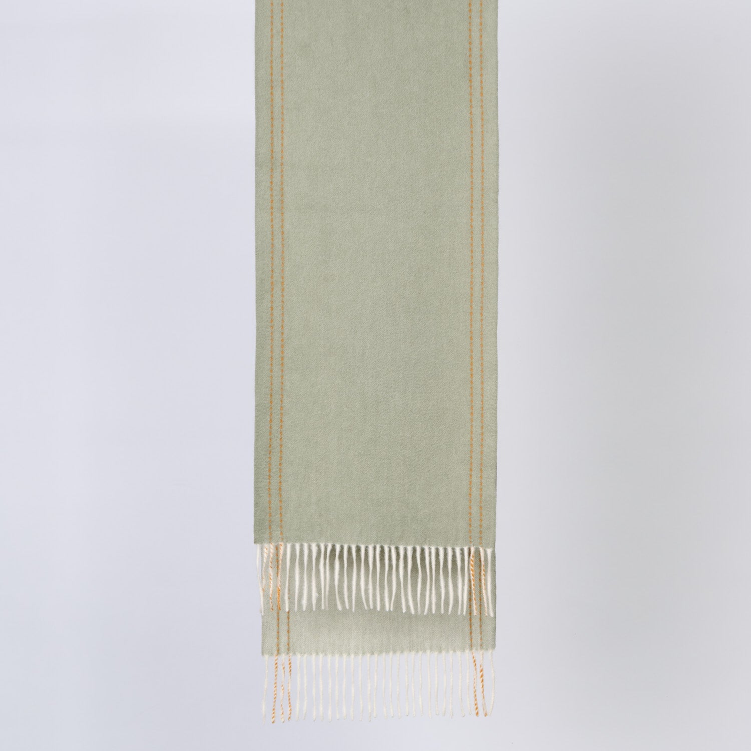 Green wool fabric with white fringe on a light gray background