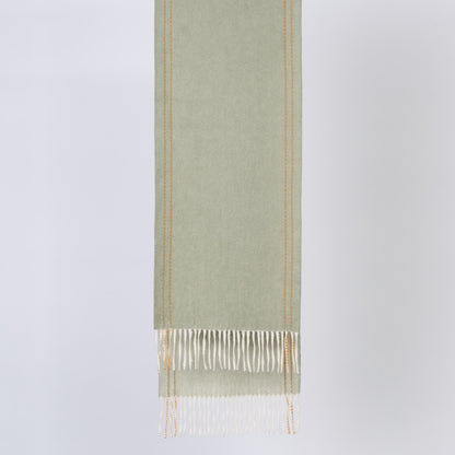 Green wool fabric with white fringe on a light gray background
