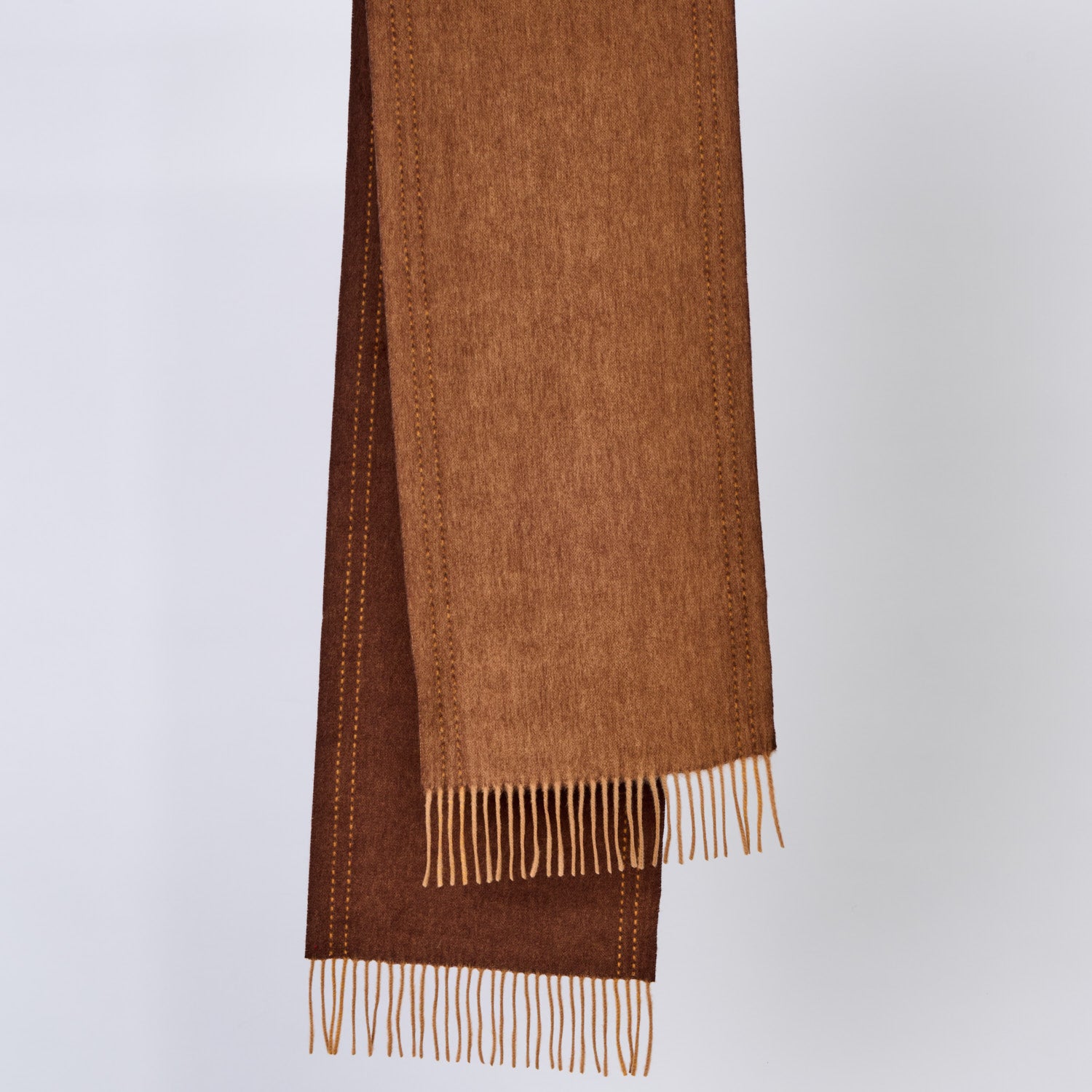 Brown wool scarf with fringe on a light gray background