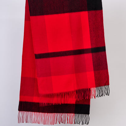 Red and black checkered wool scarf with fringes on a light gray background