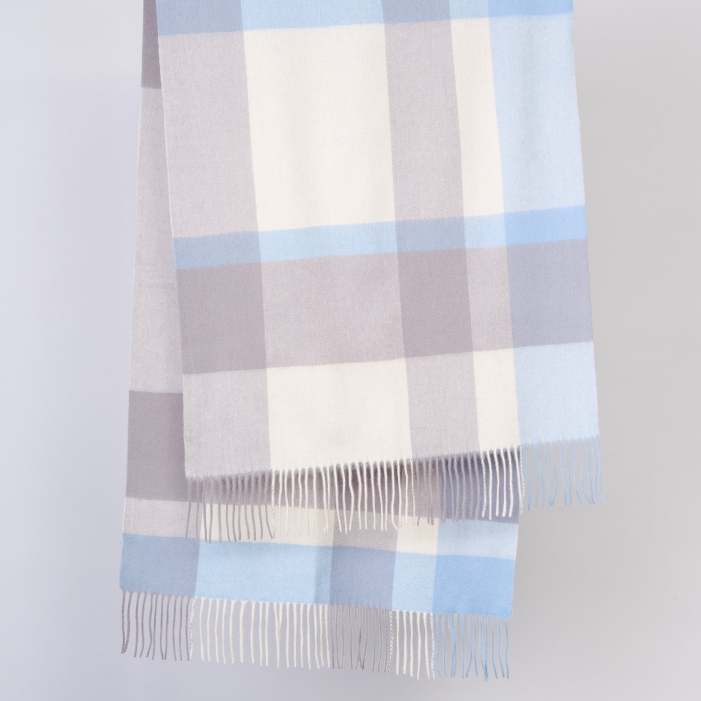 Plaid wool shawl with blue and gray pattern on a light gray background