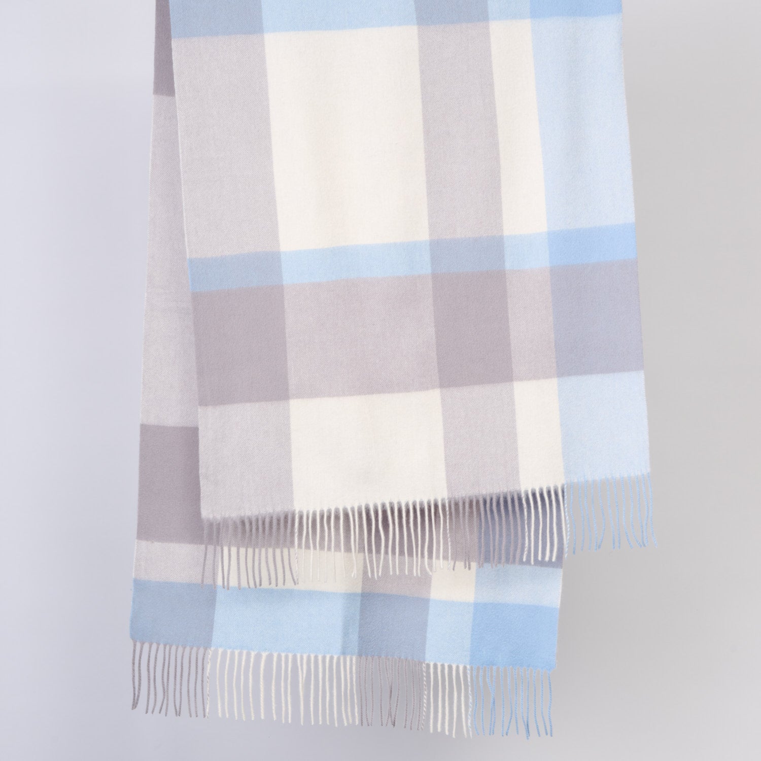 Plaid wool shawl with blue and gray pattern on a light gray background