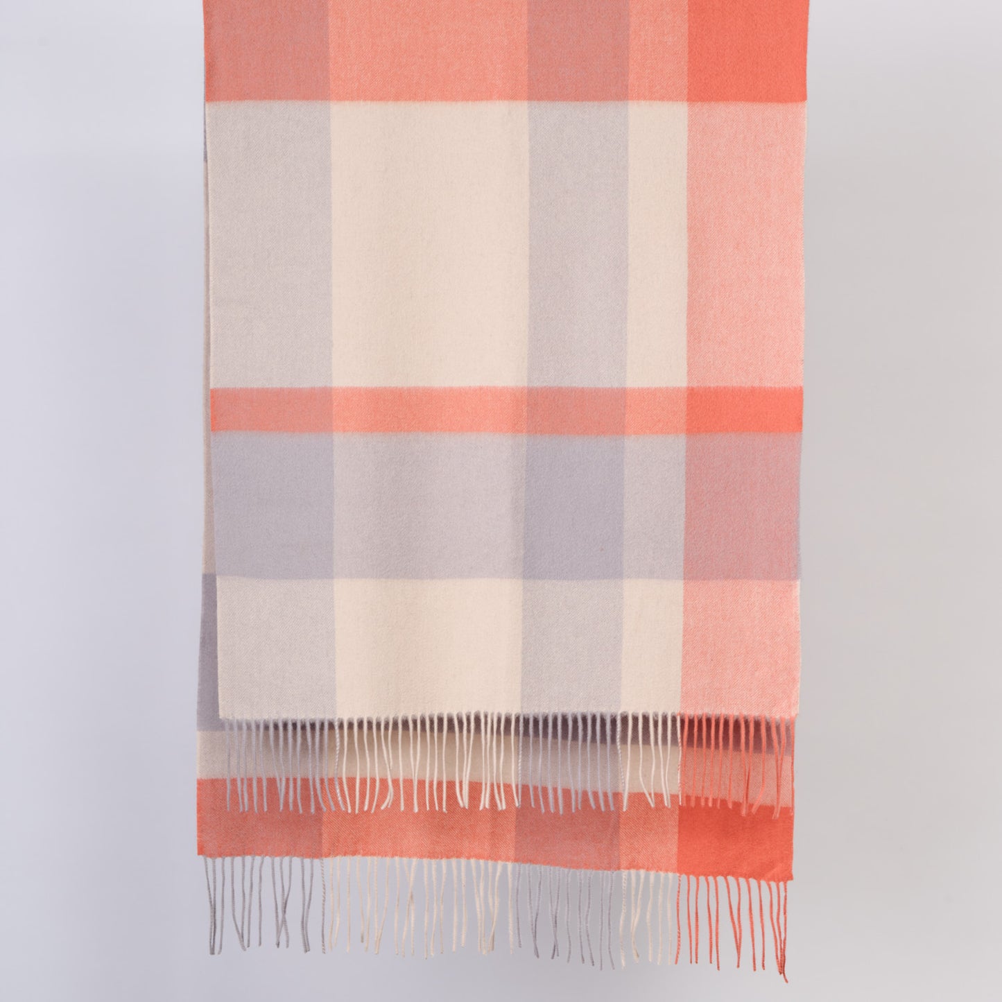 Plaid scarf with orange, beige, and light purple colours on a light gray background