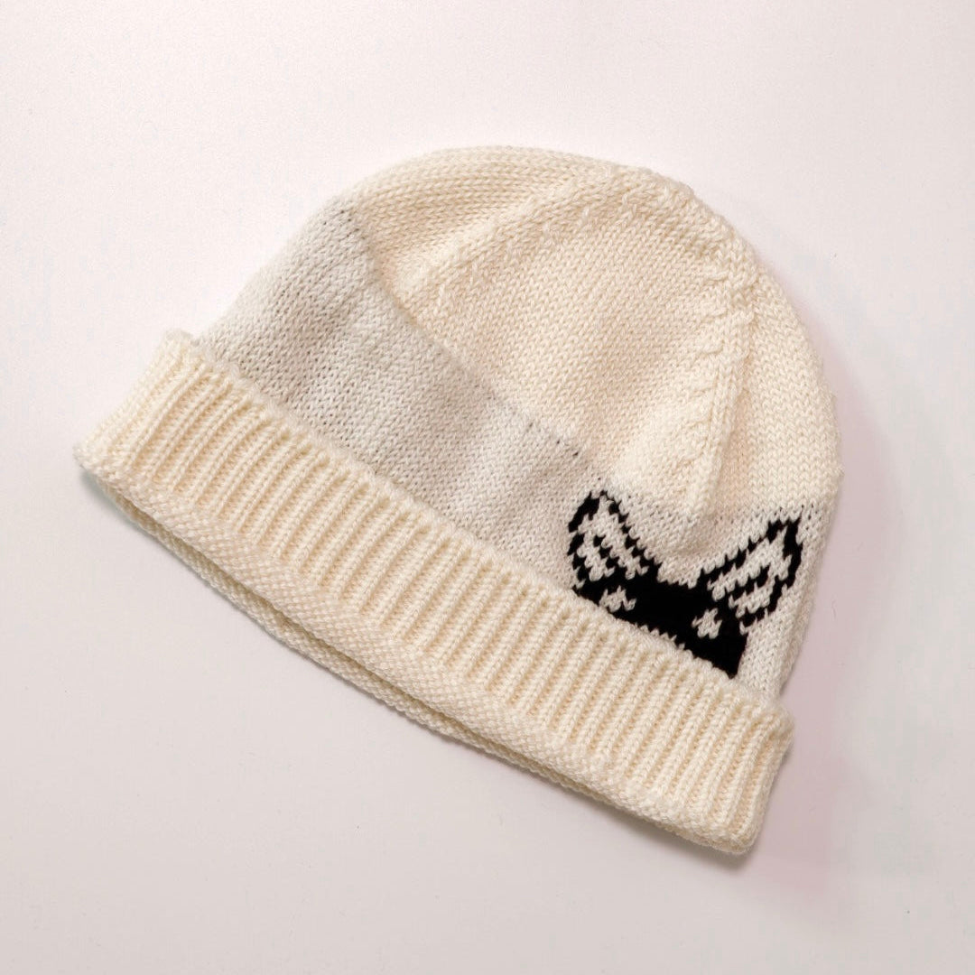 Knitted beanie with a black and white design on a light gray background