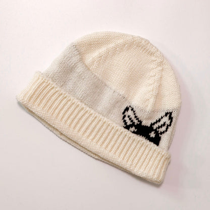 Knitted beanie with a black and white design on a light gray background