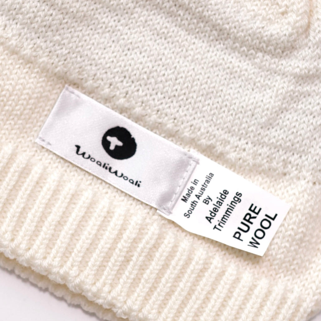 Close-up of a white knit garment with a visible label on a white background