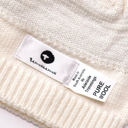 Close-up of a white knit garment with a visible label on a white background