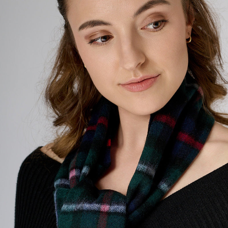 Woman wearing a plaid scarf  (red, blue, green) against a neutral background.