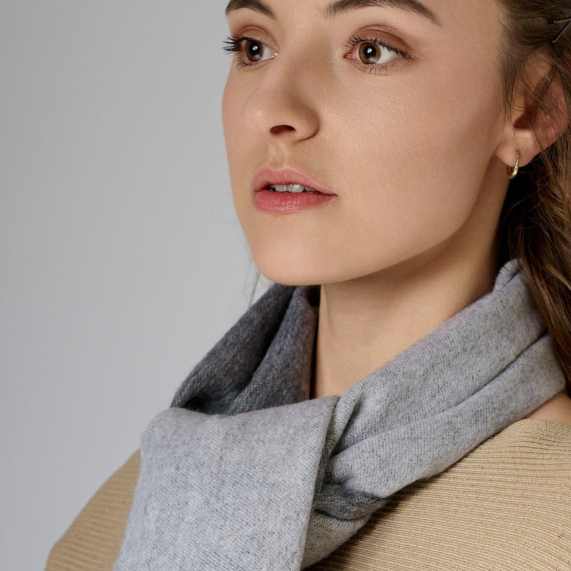 Woman wearing a gray scarf against a plain background