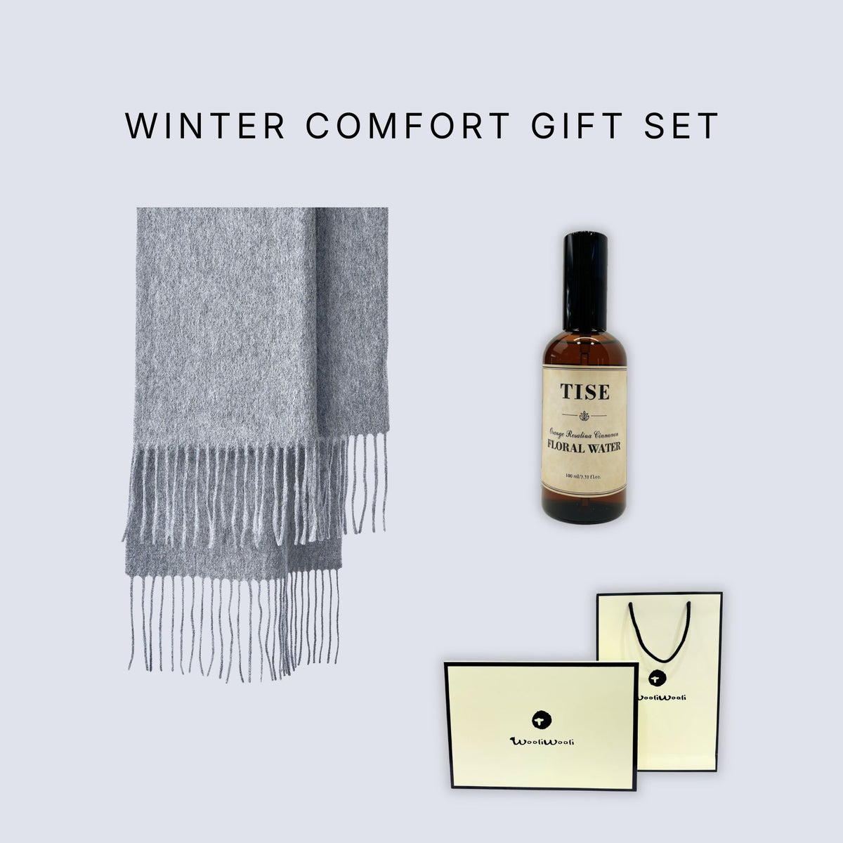 Winter Comfort Gift Set featuring a light gray fringed scarf, a bottle of Tise Herbal Water, and branded cream-colored gift cards and a bag on a light gray background.