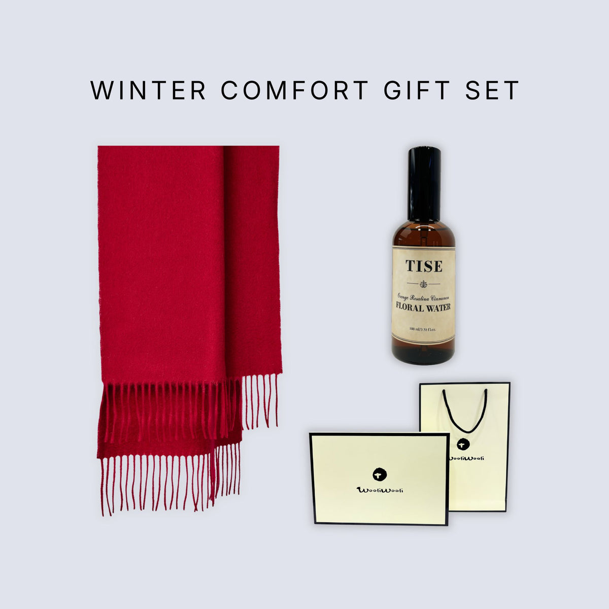 Winter Comfort Gift Set featuring a vibrant red scarf with fringe, a bottle of Tise Normal Water, and cream-colored branded gift packaging on a light gray background.