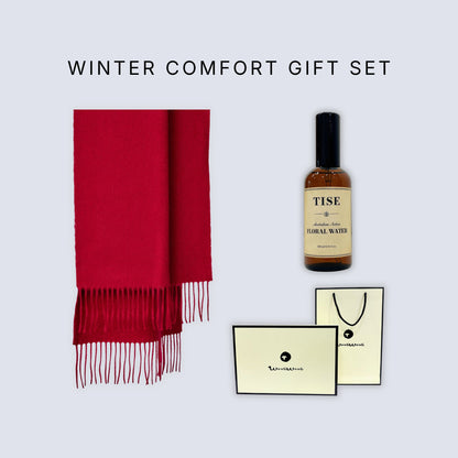 Winter Comfort Gift Set featuring a vibrant red scarf with fringe, a bottle of Tise Herbal Water, and branded gift packaging on a light gray background.