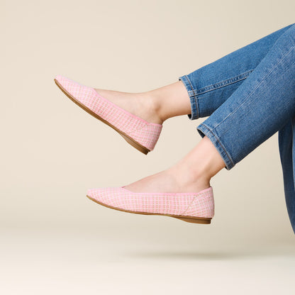 Pink checkered shoes worn with blue jeans on a beige background