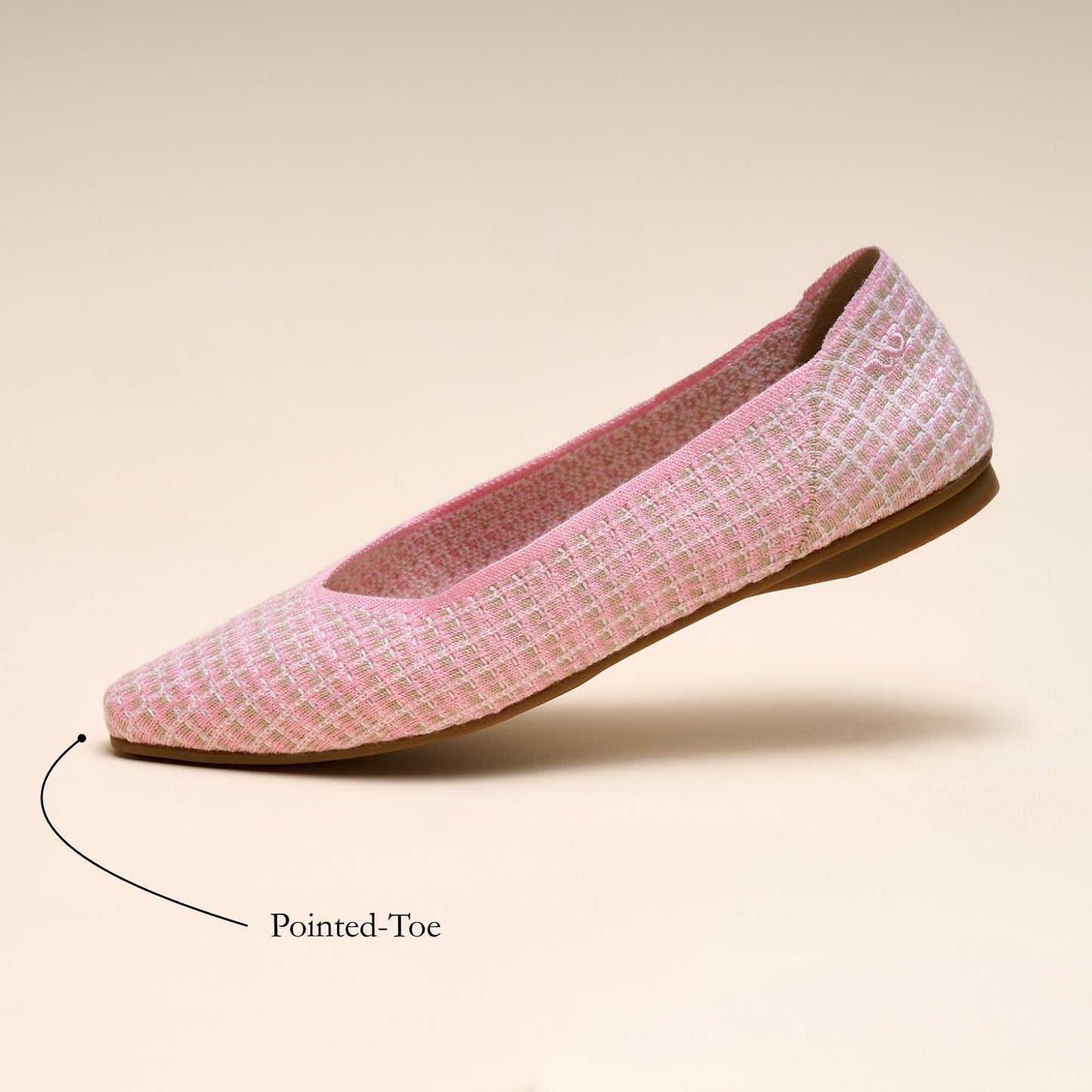 Pink flat shoe with pointed-toe feature on a beige background