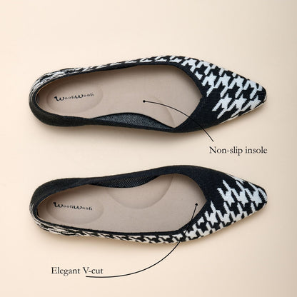 Pair of black and white patterned flats with a non-slip insole on a beige background